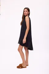 Vestido corto beige de lino, sin mangas, con escote redondo y detalle de abertura en forma de lágrima en el pecho. Presenta diseño holgado y dobladillo asimétrico más largo en la parte trasera con volados.