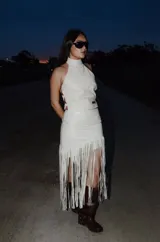 Top de cuero color blanco, de diseño halter con cuello alto y espalda descubierta con tiras ajustables laterales.