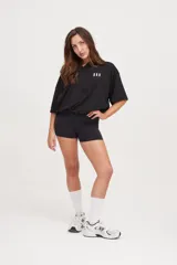 Camiseta negra de manga corta con cuello en V, corte holgado y cordón ajustable en la cintura.