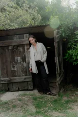 Campera de punto color beige, con cierre frontal y detalle en cuero en el tirador. Presenta un diseño de líneas verticales y cuello alto, con un corte holgado y cómodo.