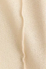 Top de punto fino y liviano color beige, con escote bote, mangas largas acampanadas con tiras decorativas en los puños y costuras visibles en la parte frontal y las mangas.