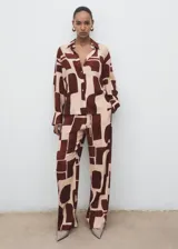Camisa de viscosa fluida con estampado geométrico en tonos marrón y beige, cuello camisero, manga larga y cierre frontal con botones.