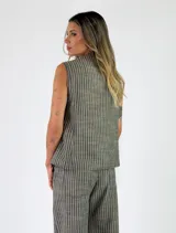 Chaleco sastrero sin mangas, de color beige con diseño de rayas verticales, cuello en V y cierre frontal con botones.