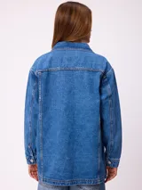 Campera de jean de corte oversize, color azul lavado, con cierre frontal de botones metálicos, bolsillos frontales con solapa en el pecho y bolsillos laterales inferiores.
