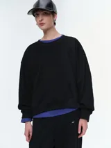 Buzo de corte oversize con escote redondo y mangas largas, confeccionado en una mezcla de algodón y poliéster con textura suave.