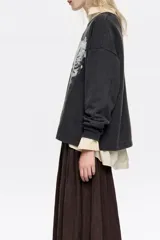 Sudadera de corte recto y holgado, con cuello redondo y manga larga. Presenta un estampado artístico de paisaje montañoso con un ciervo en el frente.