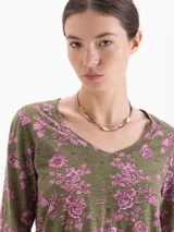 Remera de manga larga con cuello redondo, confeccionada en tejido de punto con estampado floral en tonos verdes y rosados.