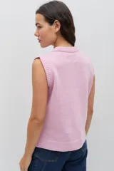 Chaleco de punto color celeste, con diseño de trenzas y pequeñas flores bordadas a mano en color marrón oscuro. Presenta cuello redondo y terminaciones acanaladas.