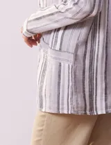 Sobrecamisa de lino y rayón a rayas verticales en tonos grises y blancos, con cuello camisero, cierre frontal con botones, mangas largas y bolsillos de parche en el delantero.