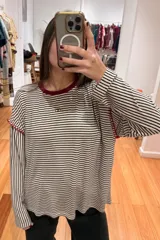 Remera de manga larga con diseño a rayas horizontales en azul marino y bordó. Presenta cuello redondo en color crema, costuras decorativas a contratono hechas a mano en las sisas y logo bordado en el frente.