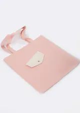 Bolso tote color rosa de material sintético con asas al tono. Presenta un bolsillo externo con solapa y botón a presión.