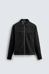 Sobrecamisa de denim de algodón negro con efecto lavado, corte relajado (relaxed fit). Presenta cuello solapa, cierre frontal con cremallera, manga larga con puño abotonado y bolsillo plastrón en el pecho.