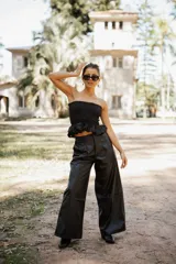 Pantalón de tiro alto confeccionado en cuero sintético, de corte amplio y pierna ancha con costura horizontal a media altura.