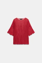 Top rojo de punto con textura efecto arrugado, cuello redondo y mangas cortas holgadas.