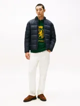 Campera acolchada de hombre, color azul marino, con cuello alto y cierre frontal de cremallera. Presenta un diseño acolchado horizontal y el logo de Tommy Hilfiger bordado en el pecho.