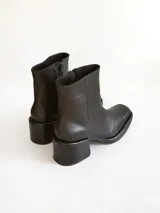Bota corta de cuero negro con punta cuadrada y taco bloque texturizado. Presenta cierre lateral y costura central en el empeine.