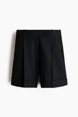 Short negro de tiro alto en mezcla de lino, algodón y viscosa, con pliegues frontales y posteriores, bolsillos al bies y bajos con vuelta cosida.