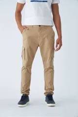 Pantalón cargo de hombre con fit slim, confeccionado en una mezcla de algodón y elastano. Presenta cierre de cremallera y botón, bolsillos laterales tipo cargo, pasa cinto y terminación con puños elásticos en los tobillos.