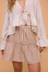 Minifalda color beige con textura arrugada, cintura elastizada y volado en el ruedo.