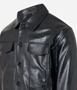 Campera trucker negra de cuero sintético con textura crocco, cuello inglés, cierre con botones, bolsillos con solapa en el pecho y puños abotonados.