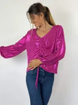 Blusa fucsia metalizada con escote en V, mangas largas abullonadas y fruncido ajustable en el centro.