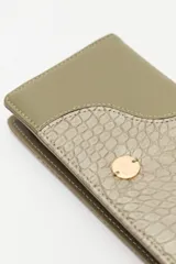 Billetera de mano con textura efecto cocodrilo, color beige, con cierre perimetral y tira de muñeca desmontable.
