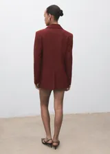 Chaqueta de traje color bordó con solapas de muesca, cierre frontal de un botón, bolsillos con solapa y forro interior.