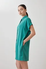 Túnica verde de lyocell con cuello camisero, manga corta con dobladillo y cierre frontal con botones.