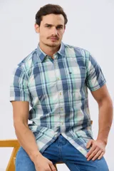 Camisa de manga corta con estampado de cuadros en tonos celestes, azules, blancos y verdes, con cierre frontal de botones y bolsillo ojal en el pecho.