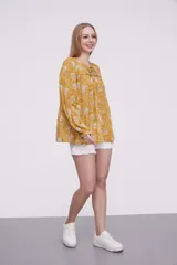 Blusa marrón con estampado de flores color naranja y blanco, con cuello redondo con abertura y mangas largas abullonadas.