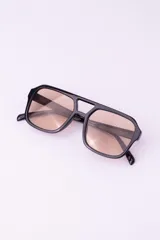 Lentes de sol con armazón de policarbonato negro y cristales tintados en tono ámbar, con diseño de estilo retro y protección UV400.