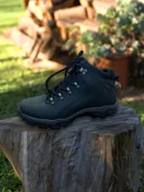 Botín de trekking color negro, con diseño acordonado, suela de goma antideslizante y refuerzos en la zona del tobillo.