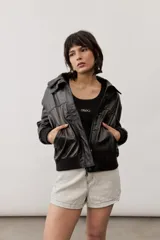 Chaqueta de cuero color negro, de corte oversize, con cierre frontal y solapas.