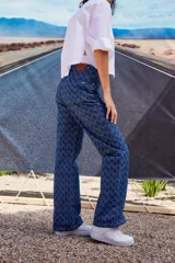 Jean de tiro bajo y corte oversize, confeccionado en denim azul con monograma grabado a láser en toda la prenda. Presenta doble botón metálico en la cintura y diseño de cinco bolsillos.