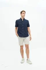 Camisa de manga corta confeccionada en una mezcla de lino y algodón, con cuello clásico, cierre frontal de botones y bolsillo en el pecho con logo bordado.