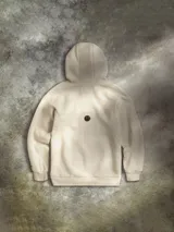 Buzo con capucha color beige, confeccionado en mezcla de algodón. Presenta un diseño bordado y flocado en el centro del pecho inspirado en Bright Tree Village de los Ewoks, con detalles adicionales que incluyen insignias rebeldes, mensajes en Aurebesh y coordenadas de Endor. Cuenta con bolsillo tipo canguro, capucha forrada con costuras Trapunto y puños y dobladillo acanalados.