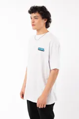 Remera blanca de algodón con estampa en la espalda de la palabra "FRESH" en letras celestes con contorno negro, sobre dos manos que sostienen latas de aerosol con caras de gato.