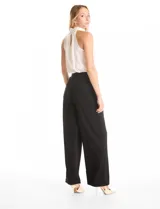 Pantalón palazzo de tiro alto confeccionado en crepe fluido. Presenta pierna ancha, pinzas frontales, bolsillos laterales y detalle de cadenas doradas integradas en la pretina.