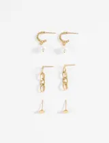 Set de tres pares de caravanas doradas de acero: aros tipo argolla con textura y dije de perla, aros colgantes con eslabones de cadena y aros tipo botón con textura.