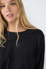 Remera básica negra de manga larga con cuello redondo y corte regular, confeccionada en tejido de punto liso de algodón.