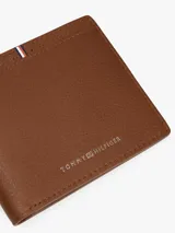 Billetera plegable de piel granulada color marrón, con logo metálico de la marca en la parte inferior frontal y detalle de cinta tricolor distintiva en la parte superior.