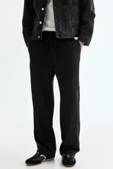 Pantalón negro de corte relajado, confeccionado en mezcla de lino y viscosa, con cintura elástica con cordón de ajuste y bolsillos laterales.