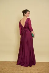 Vestido largo bordó de fiesta, con escote en V pronunciado, nudo drapeado en la cintura y tajo frontal. Las mangas son tres cuartos en tul translúcido con detalles sutiles.