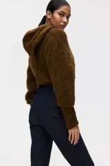 Jean de tiro alto con corte acampanado desde la rodilla. Presenta un diseño de denim oscuro con pliegues frontales y traseros, cierre con botón oculto y bolsillos traseros decorativos.