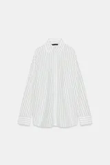 Camisa blanca de manga larga con cuello solapa y rayas verticales finas en color gris o celeste pálido. Presenta un calce oversize y cierre frontal con botones.