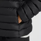 Campera puffer New Balance de color negro, con diseño acolchado, capucha integrada y cierre frontal bidireccional. Presenta el logo de la marca estampado en el pecho y puños elásticos.