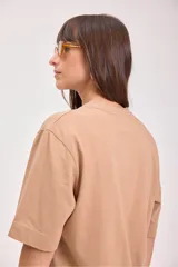 Remera de algodón color camel, corte holgado y manga corta, con un pequeño bordado de un sol en el pecho.