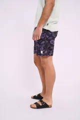 Short de baño negro con estampado de hojas y flores violetas, con cintura elástica y cordón ajustable.