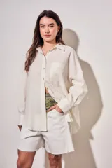 Camisa oversize color marfil, confeccionada en mezcla de viscosa y lino, con cuello camisero, cierre frontal de botones, mangas largas y bolsillo aplicado en el pecho.