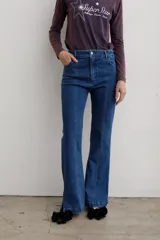 Jean de denim azul de tiro medio, con corte flare y costuras frontales destacadas.
